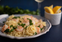 Lemon Shrimp pasta plated on old world ceramic plate and lemons photographed on a dark blue background by SoftLight Photography