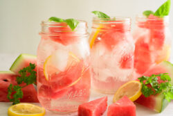 Watermelon Lemonade on ice in 3 mason jars with basil leaf garnish