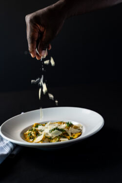 Sprinkle of cheese over ravioli with dark background