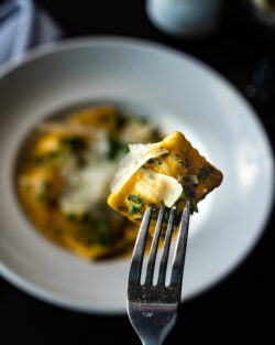 Ravioli on fork over bowl of pasta