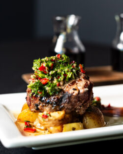 Filet Mignon steak with chimmi churri sauce with wine in background